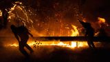 Athen, Griechenland. Freiwillige Helfer schlagen mit Zweigen auf die Flammen von Waldbränden