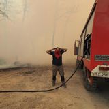 Kourkouloi, Griechenland. Ein Feuerwehrmann schützt sich mit einem Tuch gegen den Rauch eines Waldbrandes