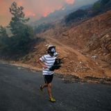 Milas, Türkei. Ein Mann rennt vor dem sich im Hintergrund nähernden Feuer davon.