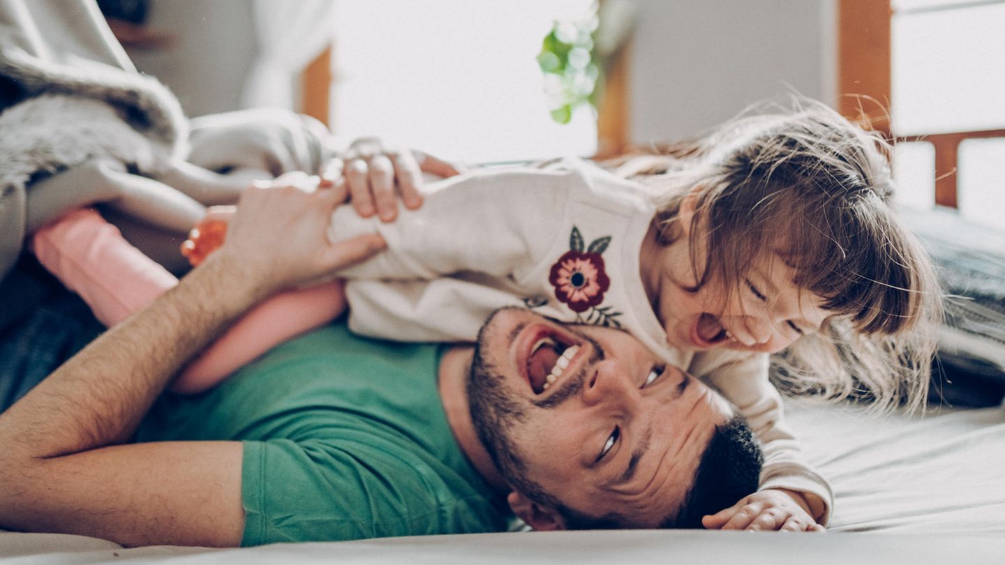 Vater und Tochter toben auf dem Boden