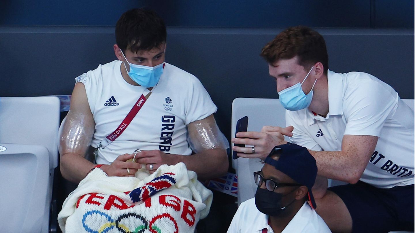 Der britische Olympiasieger Tom Daley strickte sich seine Tokio-Erinnerung selbst: einen Olympia-Pullover mit dem Logo des Teams GB und den Olympischen Ringen auf dem Rücken. Daley hatte im Synchronspringen vom Turm mit seinem Partner Matty Lee die Goldmedaille gewonnen. Strickend wurde er als Zuschauer eines Kunstspringens auf der Tribüne gesichtet.