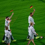 Deutsche Sportlerinnen und Sportler laufen während der Abschlusszeremonie über den Rasen.