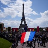 Ein Mann entrollt Fahne in den Farben der französische Nationalflagge in der olympischen Fanzone im Trocadero-Garten.