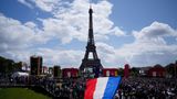 Ein Mann entrollt Fahne in den Farben der französische Nationalflagge in der olympischen Fanzone im Trocadero-Garten.