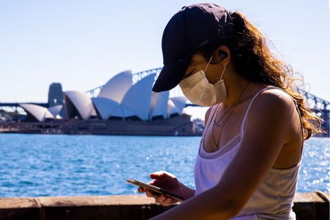 Während des neuen Lockdowns in Sydney spaziert eine Frau mit Mobiltelefon im Royal Botanical Garden