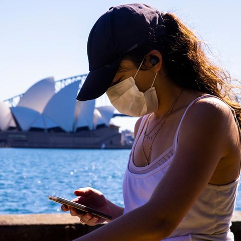 Während des neuen Lockdowns in Sydney spaziert eine Frau mit Mobiltelefon im Royal Botanical Garden