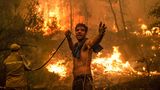 Ein Bewohner des Urlaubsortes Pefki im Norden der Insel hält einen Wasserschlauch, um die Feuerwehrleute zu unterstützen. Der Ort entkommt dem Inferno so gerade eben, der Dorfkern bleibt - bislang - unberührt.