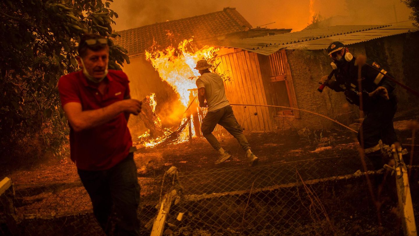 Wie dramatisch die Lage teilweise ist, zeigt diese Aufnahme: Bewohner des Urlaubsortes Pefki und ein Feuerwehrmann versuchen, die Flammen einzudämmen, die bereits ein Haus und einen Schuppen erfasst haben.