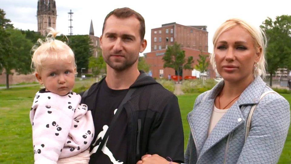 Weissrussland: Fall Timanowskaya – Ein Paar aus Belarus spricht über seine Verfolgung Das weißrussische Paar steht mit ihrer Tochter auf einer Wiese in Deutschland