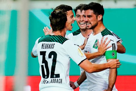 Vier Fußballspieler in weißen Trikots und Hosen jubeln gemeinsam