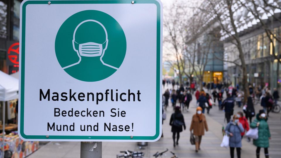 Ein Hinweisschild auf die Maskenpflicht hängt auf der Einkaufsstraße Prager Straße an einem Lampenmas