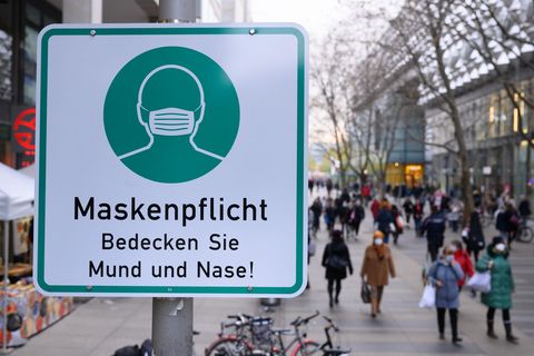 Ein Hinweisschild auf die Maskenpflicht hängt auf der Einkaufsstraße Prager Straße an einem Lampenmas