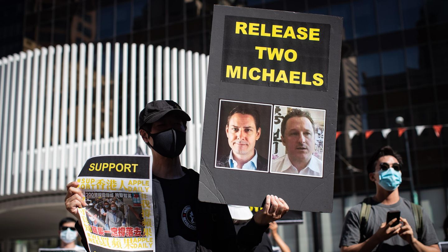 Eine Person hält ein Schild mit Fotos von Michael Kovrig und Michael Spavor