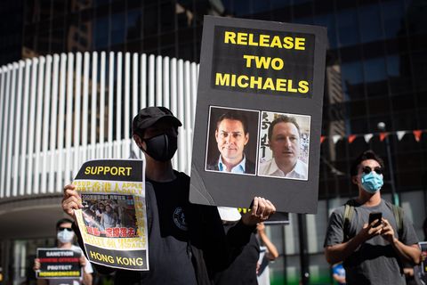 Eine Person hält ein Schild mit Fotos von Michael Kovrig und Michael Spavor