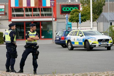 Zwei Polizisten sichern nach Schüssen auf einem Parkplatz im Kristianstader Stadtteil Nasby den Tatort