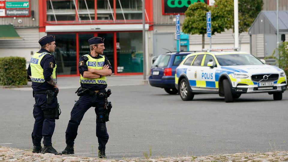 Zwei Polizisten sichern nach Schüssen auf einem Parkplatz im Kristianstader Stadtteil Nasby den Tatort