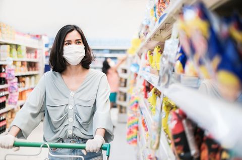 Eine Frau schiebt ihren Einkaufswagen durch einen Supermarkt