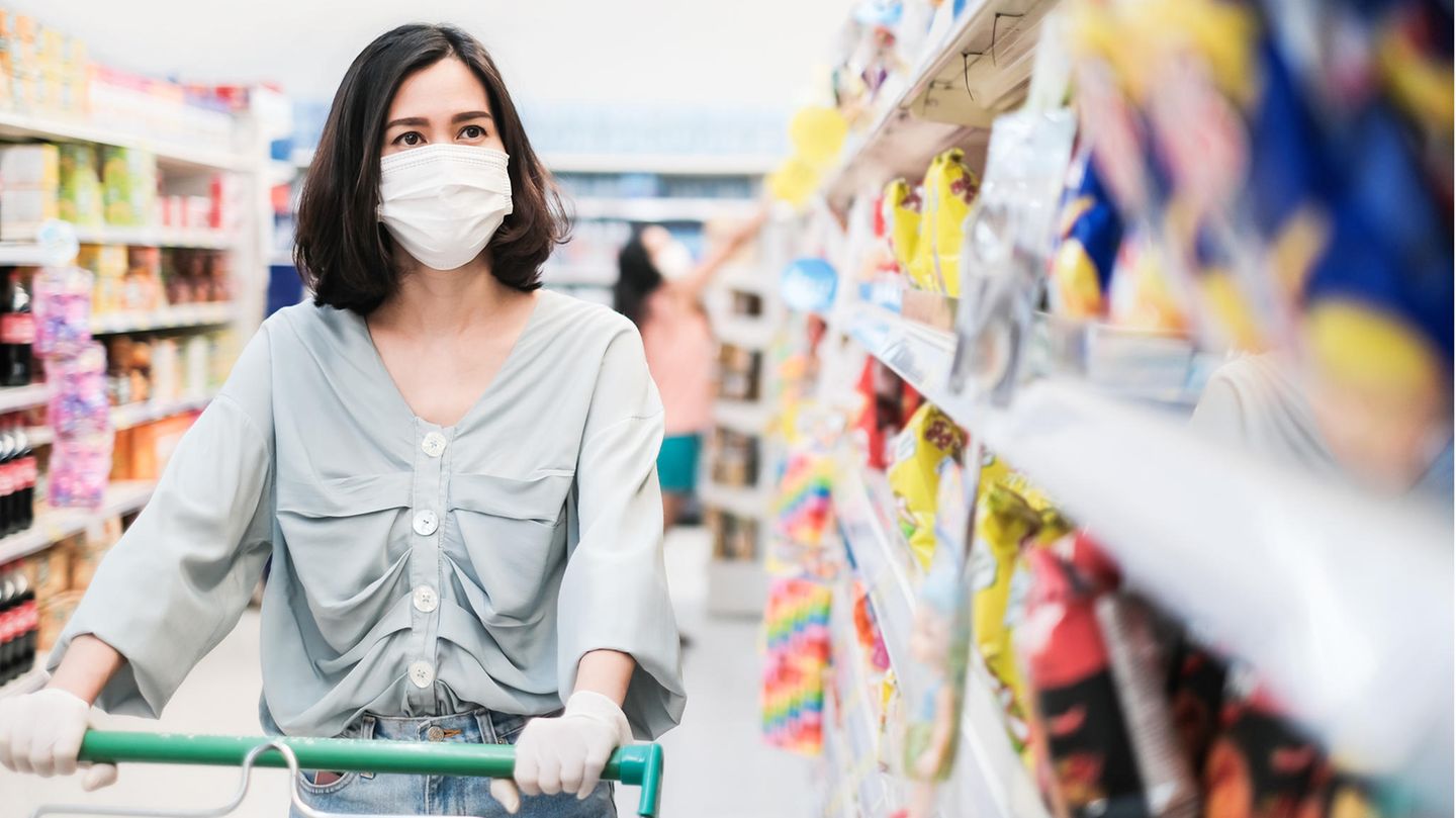 Eine Frau schiebt ihren Einkaufswagen durch einen Supermarkt