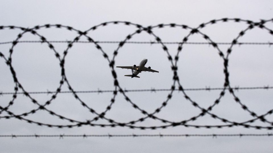 Ein Flugzeug startet am Flughafen Hannover – fotografiert durch Stacheldraht am Flughafenzaun