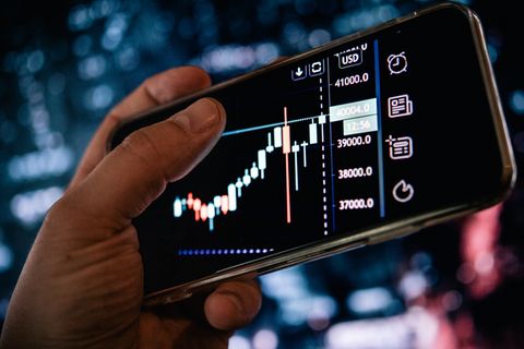 Inflation: Ein Smartphone-Display zeigt schwankende Aktienkurse