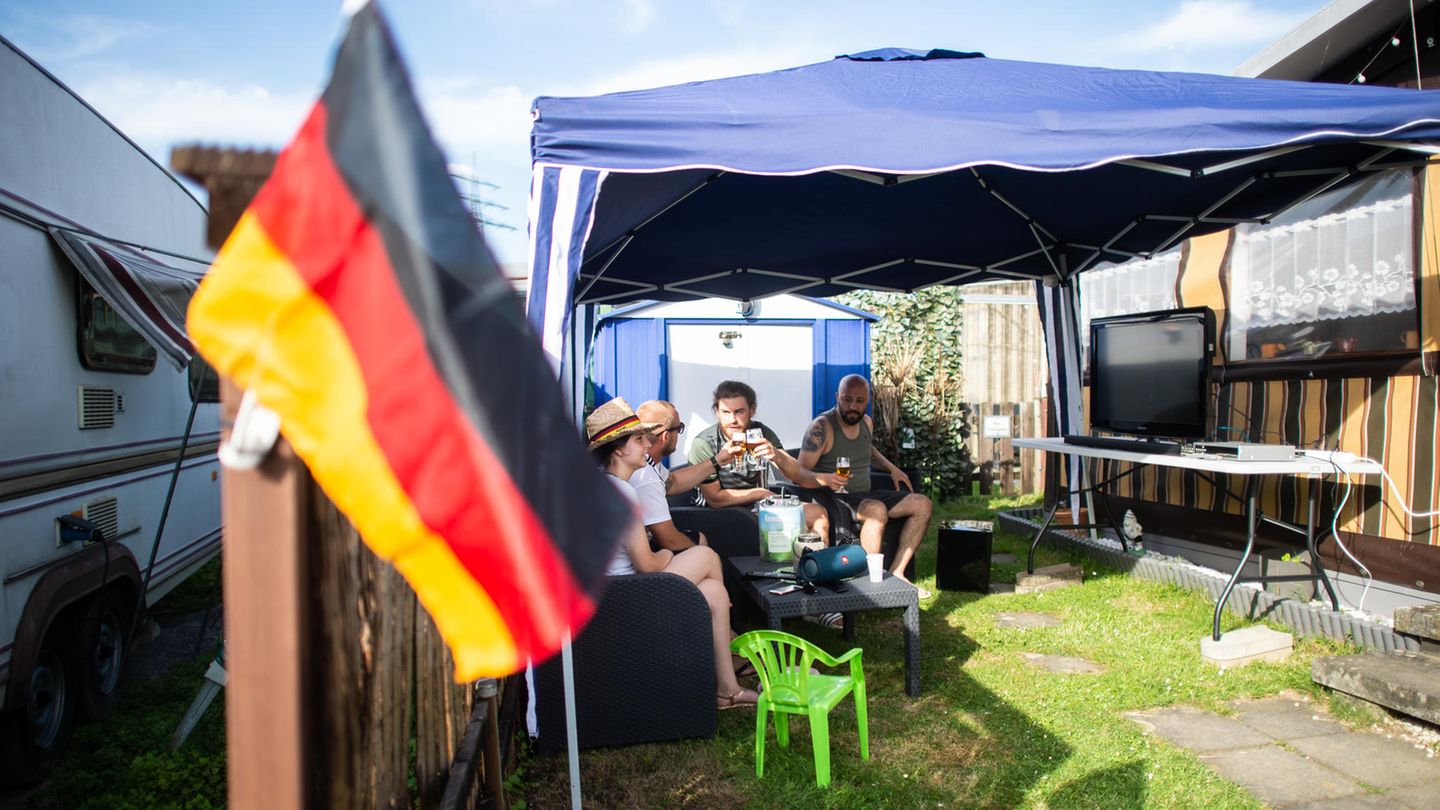 Menschen sitzen um einen Tisch auf einem Campingplatz