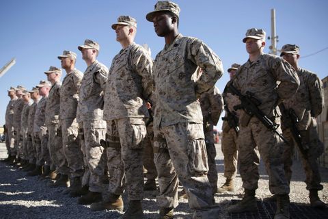 US-Soldaten in grauen Tarnfleck-Uniformen stehen auf einem staubigen Exerzierplatz in Reih und Glied