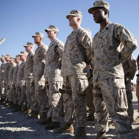 US-Soldaten in grauen Tarnfleck-Uniformen stehen auf einem staubigen Exerzierplatz in Reih und Glied