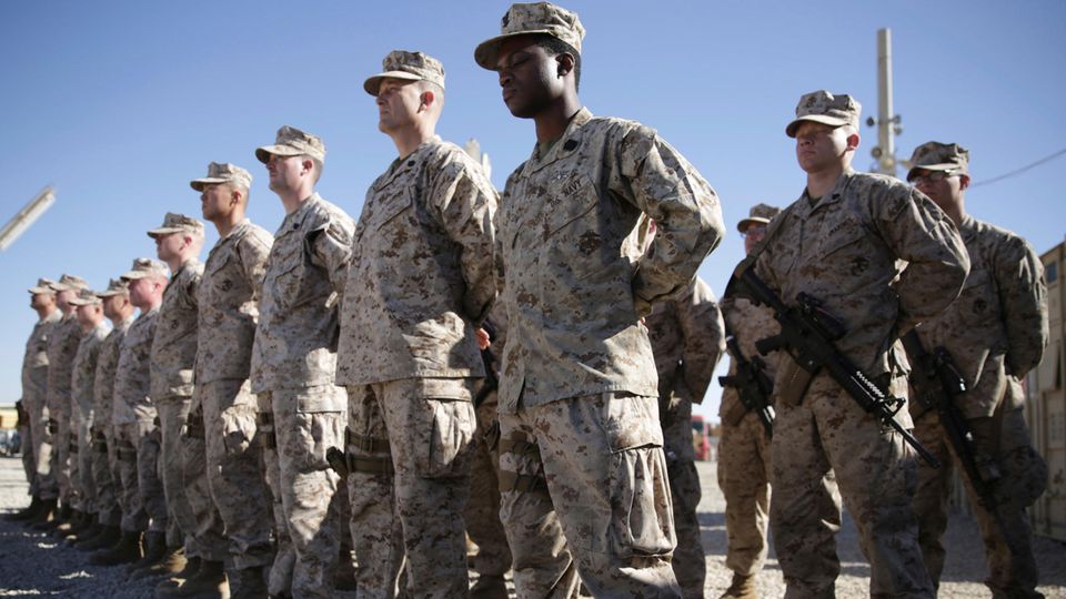 US-Soldaten in grauen Tarnfleck-Uniformen stehen auf einem staubigen Exerzierplatz in Reih und Glied