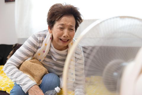 Eine ältere Dame kühlt sich vor einem Ventilator ab