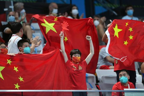 Zuschauer jubeln bei den Olympischen Spielen mit chinesischen Flaggen
