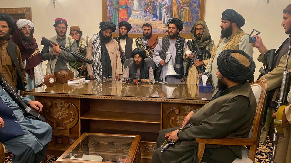Los combatientes talibanes se sientan en una habitación en el palacio presidencial en Kabul, Afganistán