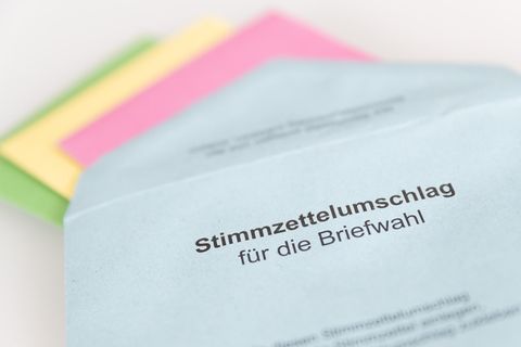 Auf einem weißen Tisch liegt ein blauer Briefumschlag mit dem Aufdruck "Stimmzettelumschlag für die Briefwahl"
