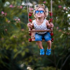 Sonnenbrillen für Kinder: Junge schaukelt mit Sonnenbrille