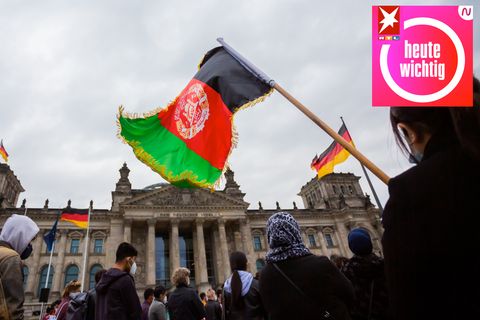 Eine Teilnehmerin hält bei einer Kundgebung vor dem Reichstagsgebäude eine Flagge Afghanistans