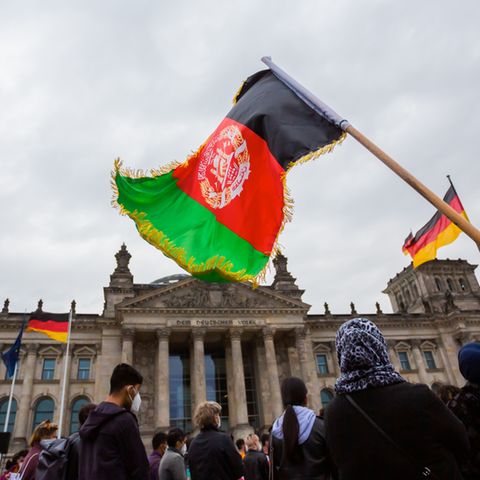 Eine Teilnehmerin hält bei einer Kundgebung vor dem Reichstagsgebäude eine Flagge Afghanistans