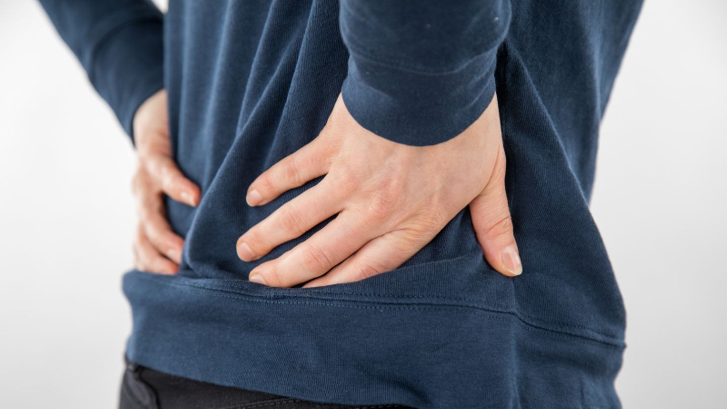 Symbolbild: Ein Mann hält sich vor Schmerzen die Hände an den Rücken.