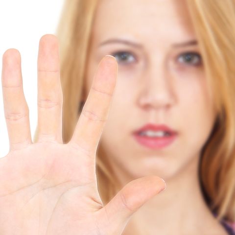 Teenagerin hält abwehrend die Hand vor sich