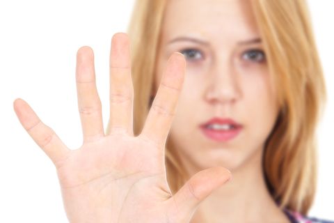 Teenagerin hält abwehrend die Hand vor sich