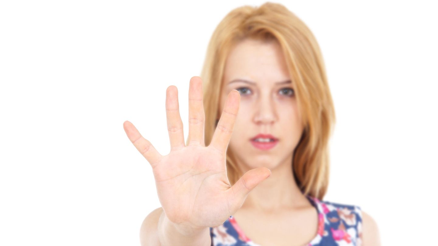 Teenagerin hält abwehrend die Hand vor sich