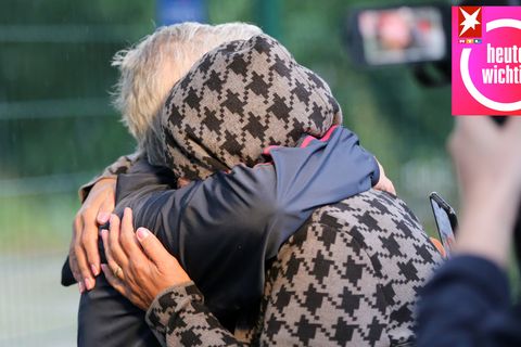 Menschen liegen sich nach der Ankunft eines Busses mit Geflüchteten aus Afghanistan vor einer Aufnahmeeinrichtung in den Armen
