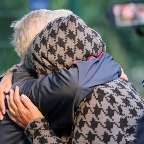 Menschen liegen sich nach der Ankunft eines Busses mit Geflüchteten aus Afghanistan vor einer Aufnahmeeinrichtung in den Armen