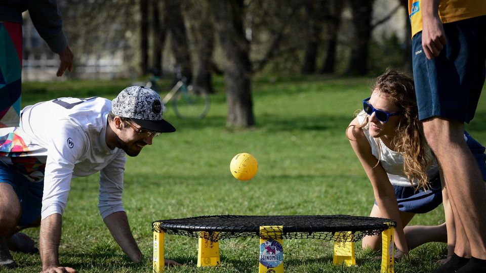 Outdoor-Spiele: Drei Erwachsene beim Spikeball spielen in einem Park