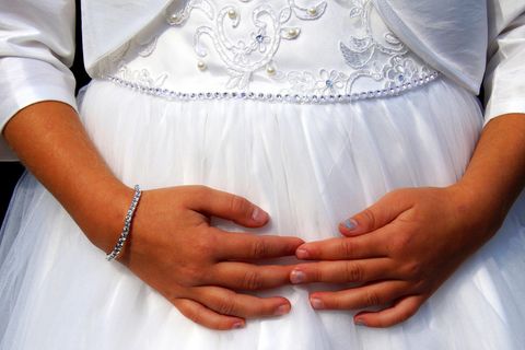 Ein Mädchen mit verschränkten Fingern trägt ein Brautkleid