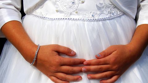 Ein Mädchen mit verschränkten Fingern trägt ein Brautkleid