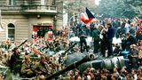 Tschechische Jugendliche stehen auf einem umgestürzten Lastwagen, während andere Prager Bürger sowjetische Panzer umzingeln