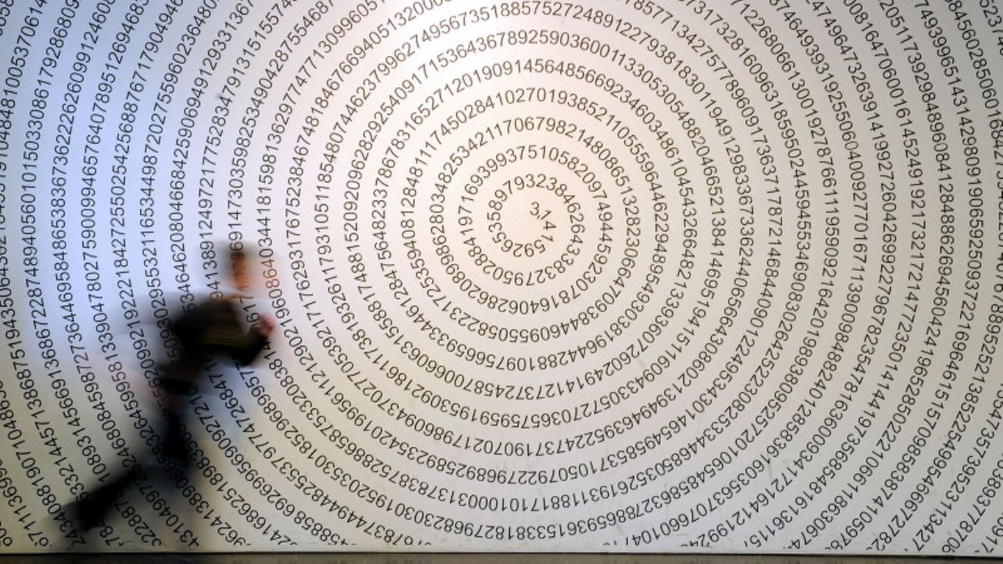 Ein Schulkind läuft im Mitmachmuseum "Mathematikum" Gießen an der auf eine Wand geschriebenen Kreiszahl Pi vorbei.