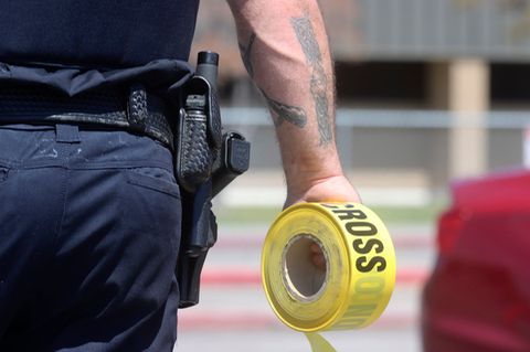 Ein Polizist hält eine Rolle mit Absperrband in der Hand