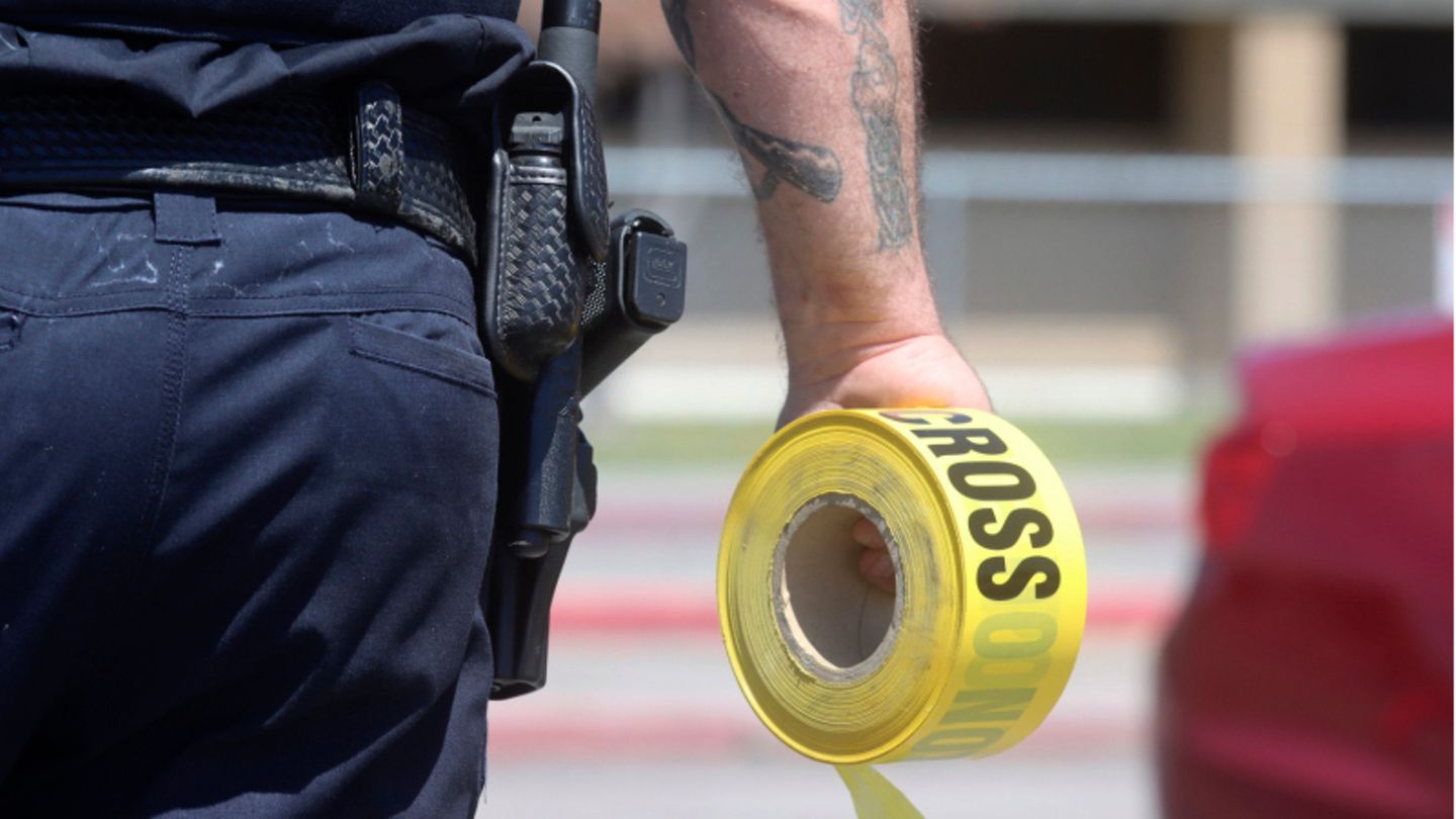 Ein Polizist hält eine Rolle mit Absperrband in der Hand