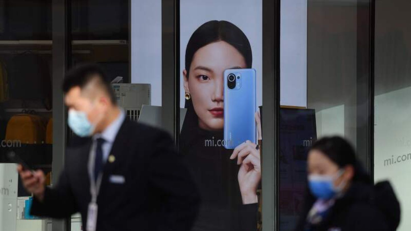 Menschen in Beijing gehen an einer Werbung für Smartphones vorbei