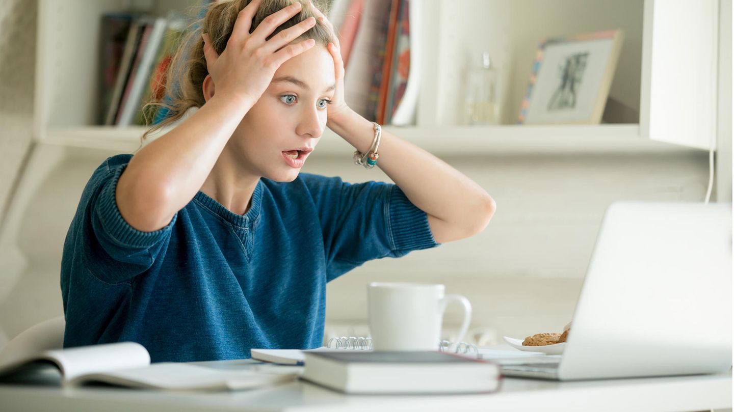 Frau sitzt vor Laptop und ist geschockt